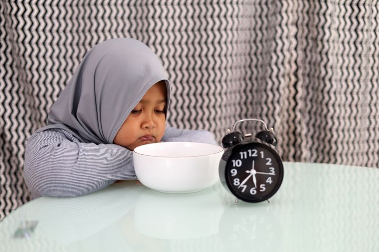 Asian muslim little girl waiting for breaking her fast. Ramadhan concept; Shutterstock ID 2271690935; purchase_order: aljazeera ; job: ; client: ; other: